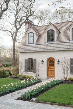 a white brick house with tulips in the front yard and landscaping around it