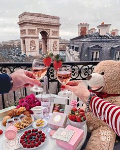 two people are toasting wine glasses with strawberries on a table in front of the arc de trioe