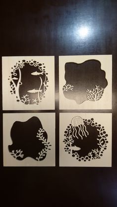 four paper cut designs with sea animals and corals in the middle, on a black surface