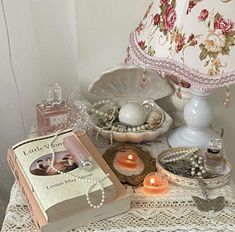 a table topped with books and candles on top of a white doily covered table