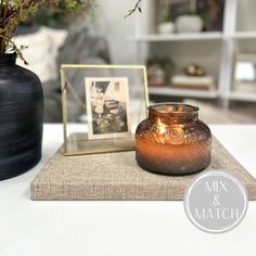 a lit candle sitting on top of a table next to a vase