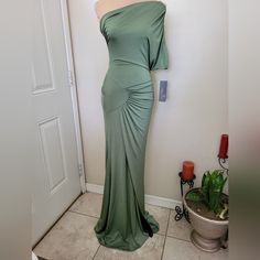 a green dress is on display in front of a door with a potted plant