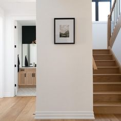 there is a framed photo hanging on the wall next to some stairs in this house