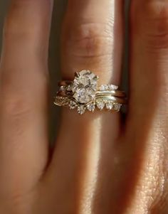 a woman's hand with two wedding rings on top of her ring and the other half of her finger