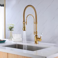 a gold faucet with water running from it's spout in a kitchen