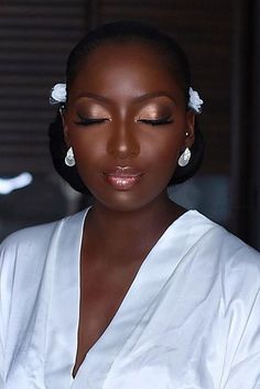 a woman in a white dress is looking down at her cell phone while wearing earrings