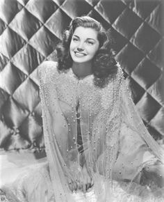 an old black and white photo of a woman wearing a dress with pearls on it