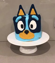 a blue and yellow cake with an angry cat face on it's side sitting on a white plate