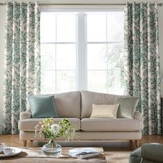 a living room scene with focus on the couch and window curtained drapes