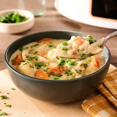 a spoonful of chicken and dumpling soup on a wooden table with other dishes