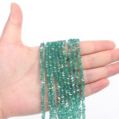 a hand is holding some green beads