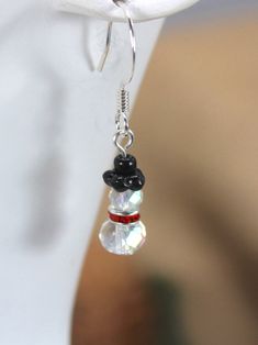 Mini Frosty the Snowman Dangle Earrings What a way to celebrate the Christmas Season and the perfect stocking stuffer.  Each Snowman Earring is made from Two-Czech Glass AB Clear Beads (4mm & 6mm). Between the two AB beads is one Crimson Crystal Spacer. The snowman's top hat is made from two black Czech Glass beads. Snowman measures 10mm long. Fish-hook ear wires and pin finding are silver-plated.  Free Shipping on orders of $35 or more. (USPS Ground Advantage only) For best results, store Jewelry in the bag provided. *Items are handmade, so each one is unique.* Returns- If a customer orders through a third-party such as a Guest or on a third-party website such as Google Shopping, return labels will not be available through Etsy. Customers will need to purchase return shipping at USPS offi Holiday Dangle Earrings With Ear Wire, Holiday Dangle Jewelry With Matching Earrings, Holiday Jewelry With Matching Dangle Earrings, Holiday Matching Drop Earrings, Holiday Jewelry With Matching Drop Earrings, Nickel-free Drop Earrings For Holiday, Earring Christmas, Snowman Earrings, Valentines Bracelets