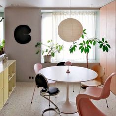 a white table with four chairs and a potted plant in the corner next to it