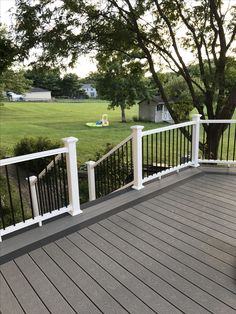 a white railing on a wooden deck in front of a tree