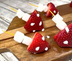 strawberries and marshmallows are arranged in the shape of triangles on a wooden board