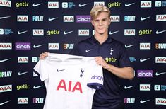 a young man holding up a soccer jersey in front of a wall with nike logos