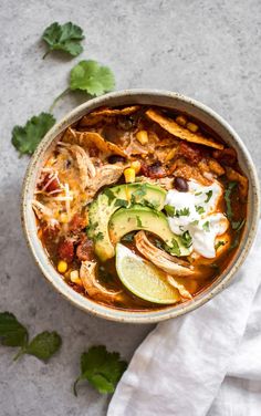 a bowl filled with chicken tortilla soup and garnished with avocado