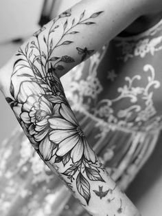 a woman's arm with flowers on it and butterflies around the arm, in black and white