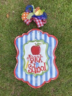 a back to school sign laying on the grass with a bow around it's neck