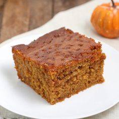 a piece of cake sitting on top of a white plate next to an orange pumpkin