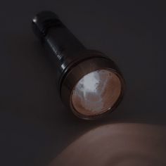 a close up shot of a flashlight on a dark surface with light coming through the lens