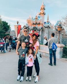 the family is posing for a photo in front of mickey mouse's castle at disneyland world