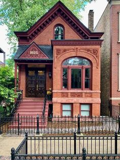 an old brick house with wrought iron fence around the front door and steps leading up to it