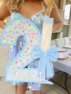 a woman holding up a sign with the number two in it's center and blue ribbon