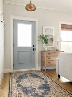 a living room with white walls and wooden floors, a rug on the floor and a blue door