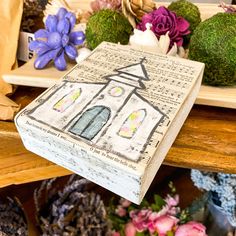 an open book sitting on top of a wooden table next to flowers and other decorations