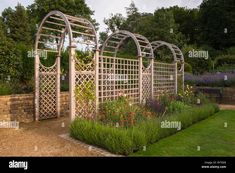 an outdoor garden with trelliss and flowers in the foreground - stock image