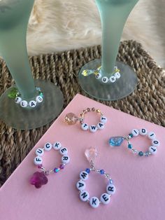 two wine glasses sitting next to each other on top of a pink card with letters