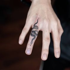 a person's hand with a snake tattoo on it