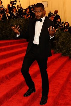 a man in a tuxedo and bow tie on the red carpet at an event