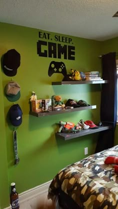 a bedroom decorated in green and black with shelves on the wall that hold game controllers