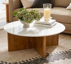 a living room with a couch, coffee table and vase filled with flowers on it