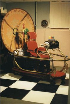 an old fashioned chair sitting in front of a large clock on a checkered floor