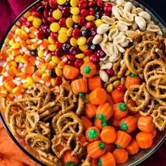 a large platter filled with candy corn, pretzels, and pumpkins