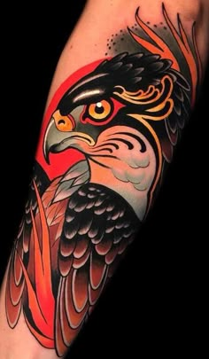 an eagle tattoo on the arm with red, black and orange colors in it's wings