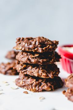 chocolate oatmeal cookies stacked on top of each other next to a bowl of oats