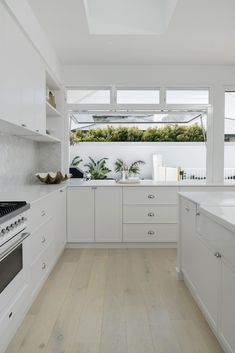 a kitchen with white cabinets and wood flooring next to an open skylight window