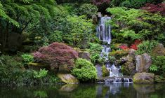 a waterfall in the middle of a pond surrounded by trees