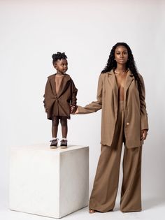 a woman standing next to a small child on top of a white block in front of a white background