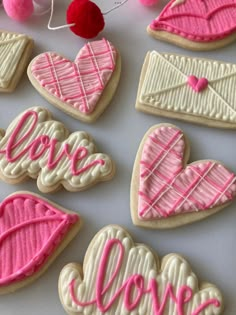 decorated cookies with the word love spelled in pink and white icing on a table