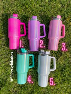 four different colored mugs sitting in the grass next to each other with numbers on them