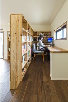 a woman sitting at a desk in front of a bookshelf filled with books