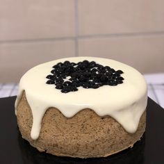 a cake with white icing and black sprinkles on it sitting on a table