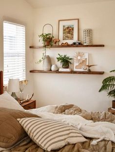 a bed room with a neatly made bed and two plants on the shelves above it