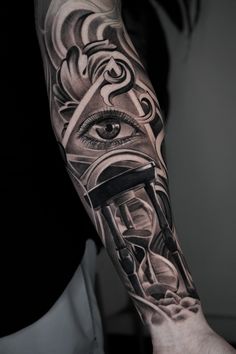 a man's arm with an all seeing eye and clock tattoo on the forearm