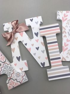 the letter n is decorated with hearts and flowers in pink, gray, white, and peach